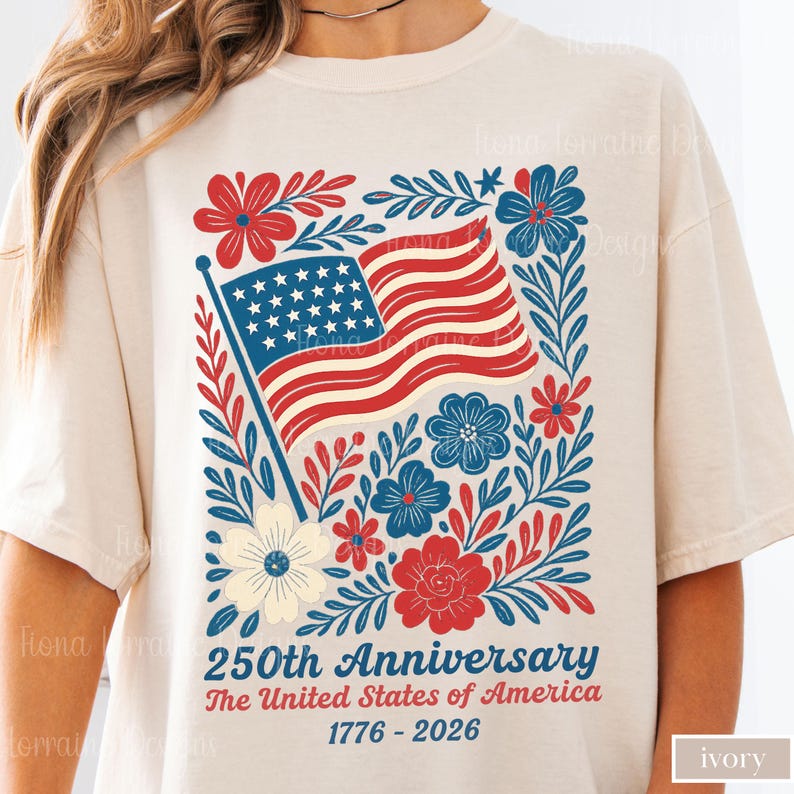 Puede incluir: Camiseta de color marfil con un dise&ntilde;o patri&oacute;tico para el 250 aniversario de los Estados Unidos. El gr&aacute;fico incluye una bandera estadounidense ondeando rodeada de elementos florales rojos, blancos y azules, con el texto "250th Anniversary The United States of America 1776-2026."