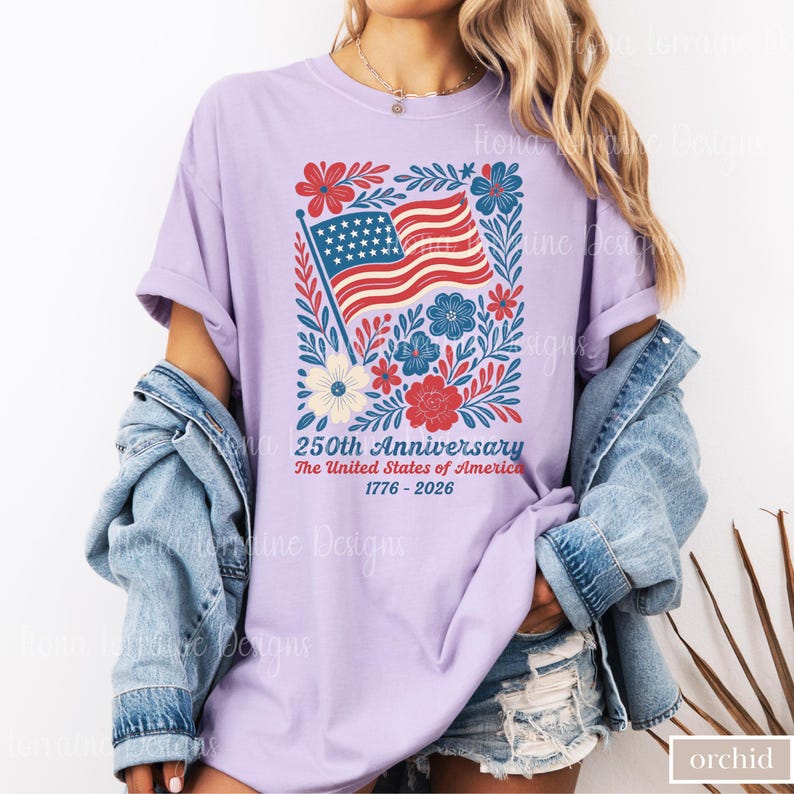 Puede incluir: Camiseta color orqu&iacute;dea con un dise&ntilde;o patri&oacute;tico para el 250 aniversario de los Estados Unidos. El gr&aacute;fico incluye una bandera americana, flores y texto. La camiseta es de un estilo c&oacute;modo e informal.