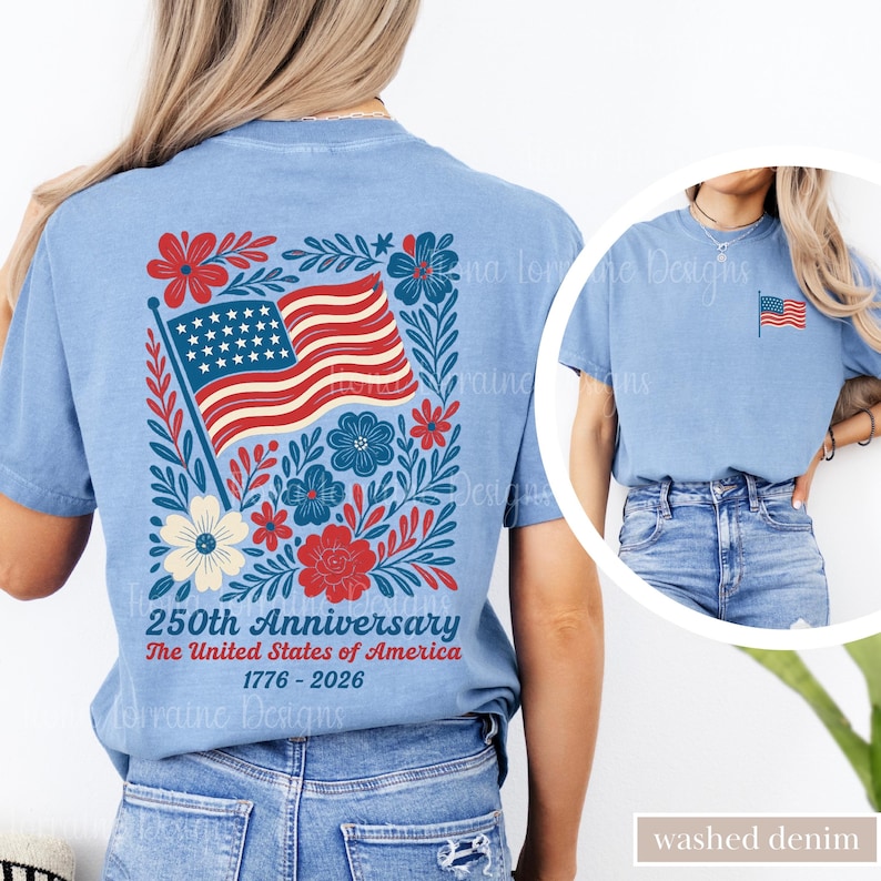 May include: Light blue t-shirt featuring a patriotic design for the 250th anniversary of the United States. The back of the shirt displays an American flag surrounded by floral elements. The text reads "250th Anniversary The United States of America 1776-2026".