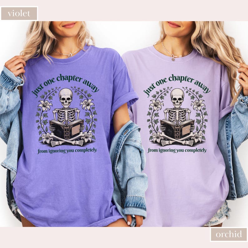 May include: Two violet and orchid-colored t-shirts with the text "just one chapter away from ignoring you completely." Each shirt features a skeleton reading a book, surrounded by floral elements.