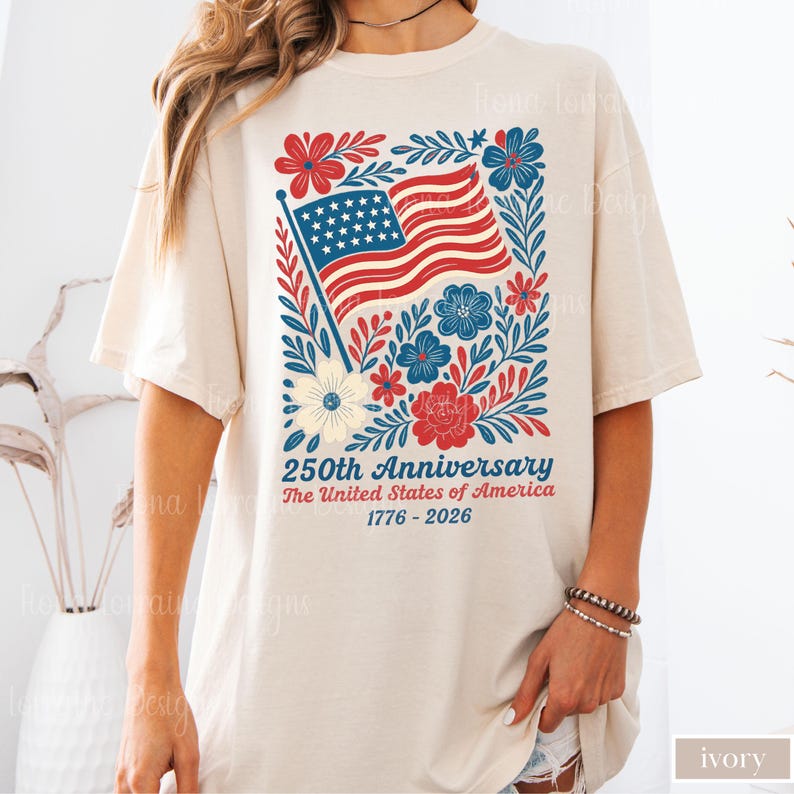 Puede incluir: Camiseta color crema con un dise&ntilde;o patri&oacute;tico para el 250 aniversario de los Estados Unidos. El gr&aacute;fico incluye una bandera estadounidense ondeando, flores rojas y azules, y el texto "250th Anniversary The United States of America 1776-2026."