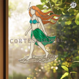 May include: A stained glass suncatcher depicting a figure with long orange hair, a turquoise seashell top, and a flowing green skirt, standing on a textured gray base. The piece is suspended by a metal chain and features the text CORTESDIGITAL.