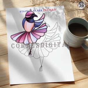 May include: A printed stained glass pattern featuring a colorful bird design. The bird has pink, purple, blue, and black details. The words "STAINED GLASS PATTERN" are printed at the top. A mug of coffee sits to the right.