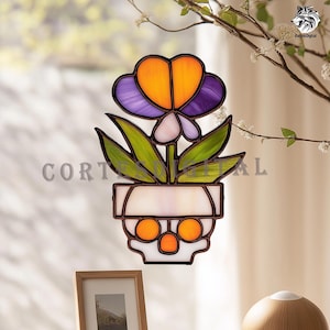 May include: Stained glass flower art piece featuring a heart-shaped orange and purple flower, green leaves, and a white pot with orange circles. The text "CORTES DIGITAL" is visible. Decorative floral art for home decor.