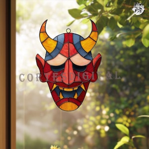 Puede incluir: Máscara de vidriera con forma de demonio rojo con cuernos y dientes amarillos. La máscara tiene una parte superior azul y amarilla, con el texto "Cortes Digital". La máscara está colgada frente a una ventana.