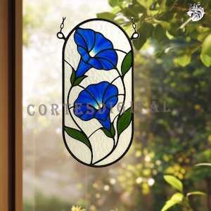 Peut inclure: Panneau de fenêtre en vitrail représentant deux fleurs de gloire du matin bleu vif avec des feuilles vertes. Les fleurs sont posées sur un fond blanc cassé texturé dans un cadre ovale noir, suspendu par des chaînes. Pour la décoration de fenêtre.