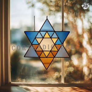 Könnte beinhalten: Ein Buntglas-Davidstern in Blau-, Gelb- und Orangetönen, der vor einem Fenster hängt. Der Stern ist in dreieckige Abschnitte unterteilt, mit einer Kette zum Aufhängen. Die Wörter "COR" und "ADIAL" sind auf dem Glas zu sehen.