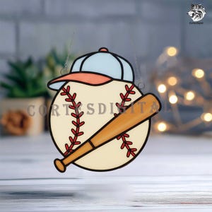 May include: A baseball-themed stained glass ornament featuring a baseball, bat, and cap. The baseball is cream-colored with red stitching, a light blue cap with an orange brim, and a wooden bat. The text "CortesDigital" is visible.