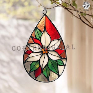 Può includere: Ornamento a goccia in vetro colorato con un design a stella di Natale. L'ornamento ha una cornice in metallo nero e presenta colori rosso, verde, bianco e marrone. È appeso a un gancio nero.