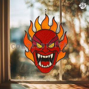 May include: A stained glass window hanging featuring a red devil face with yellow eyes and sharp white teeth, surrounded by orange and yellow flames. The word "Cortes Digital" is partially visible.