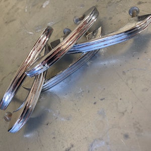 May include: Four chrome-plated cabinet door handles with a decorative grooved design. The handles have a worn finish with some rust showing through.