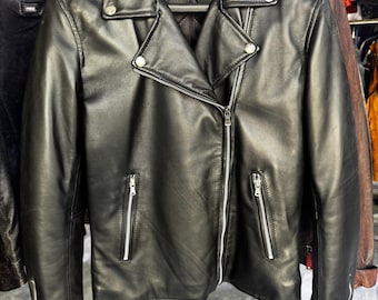 May include: A black leather motorcycle jacket with a zipper closure and two zippered pockets on the front. The jacket has a stand-up collar and a quilted lining.