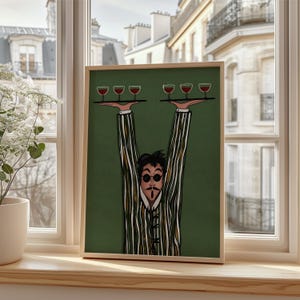 Puede incluir: Una impresión artística enmarcada que presenta una ilustración caprichosa de una persona con un traje a rayas y una máscara, sosteniendo bandejas de copas de vino. La obra de arte tiene un fondo verde y está enmarcada en madera. La imagen se muestra en un alféizar.