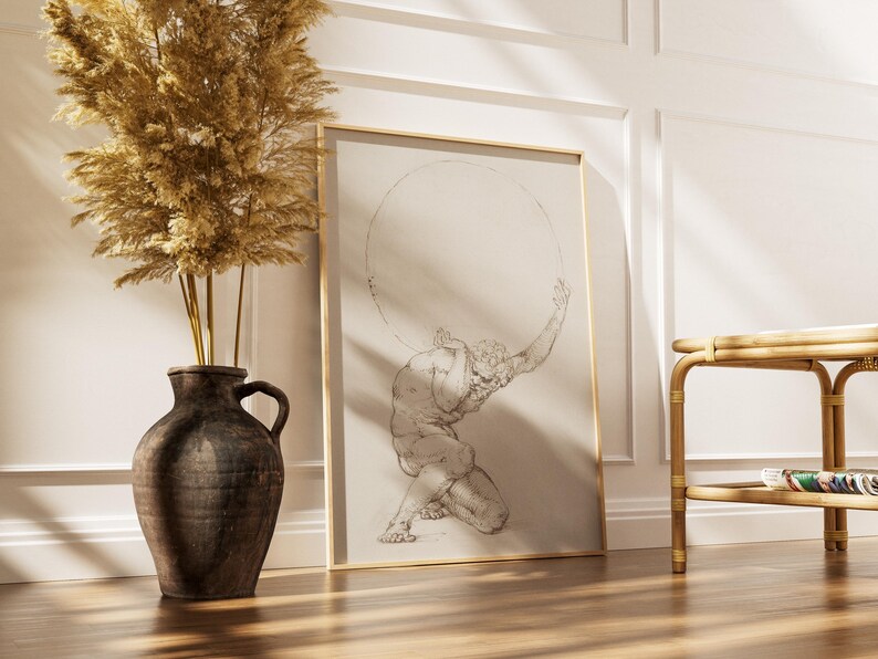 Puede incluir: Una impresi&oacute;n enmarcada de un dibujo cl&aacute;sico que representa a Atlas sosteniendo una esfera. La obra de arte est&aacute; en un marco dorado y se apoya contra una pared blanca. Un jarr&oacute;n marr&oacute;n oscuro con plantas secas y una mesa auxiliar de bamb&uacute; tambi&eacute;n est&aacute;n en la imagen.