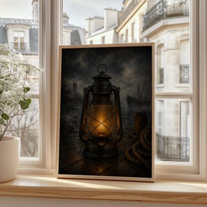 May include: A framed wall art print depicting a dark, moody maritime scene with a glowing vintage metal lantern in the foreground. The image features a wooden dock, a coiled rope, a distant ship on the water, and a lighthouse under a stormy sky.