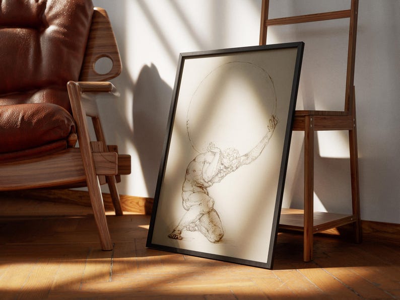 Puede incluir: Una impresi&oacute;n enmarcada que presenta un boceto de Atlas, una figura mitol&oacute;gica, sosteniendo un gran objeto circular. La obra de arte est&aacute; en un marco negro y se apoya en una estanter&iacute;a de madera. La imagen est&aacute; sobre un suelo de madera, con una silla de cuero en el fondo.
