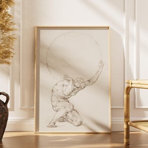 Puede incluir: Una impresi&oacute;n enmarcada de un dibujo cl&aacute;sico que representa una figura musculosa, posiblemente Atlas, sosteniendo una gran esfera. La obra de arte est&aacute; en un marco dorado y se apoya contra una pared blanca. A la izquierda hay un jarr&oacute;n oscuro con plantas secas.