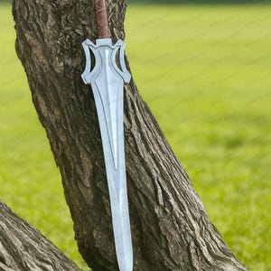 Può includere: Una spada fantasy argentata con un'impugnatura avvolta in pelle marrone, appoggiata a un tronco d'albero. La lama è lunga e a doppio taglio, con un'elsa decorativa. La spada è esposta all'aperto su uno sfondo verde.