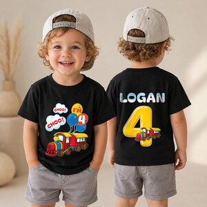 May include: A black t-shirt featuring a colorful train graphic with the text CHOO CHOO and I'M 4 on the front, and the name LOGAN with a large yellow number 4 and a small train graphic on the back, paired with grey shorts and a beige baseball cap.