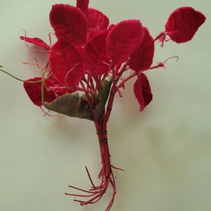 May include: A bouquet of bright pink felt flowers with a brown wire stem and roots.