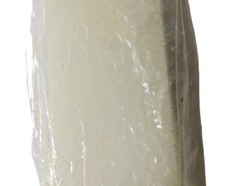 May include: A rectangular, off-white bar, possibly soap or a similar product, is encased in a clear plastic wrapper. The wrapper is slightly wrinkled, and the bar's texture is visible through the plastic. The product is suspended by a small string.
