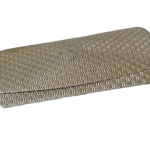 May include: A silver-colored eyeglasses case with a woven texture. The case has a rounded shape and a hinged lid. The surface has a repeating pattern of small, rectangular blocks, creating a textured appearance.