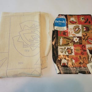 May include: A beige canvas with a printed pattern of circles and numbers. The canvas is next to a package of Patchwork Colonial Rug Patterns. The package shows a colorful rug with a patchwork design of flowers and leaves.