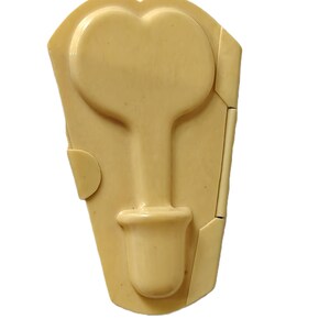 May include: A light beige, heart-shaped mold with a handle and a pot-like base. The mold is made of a solid material and has a smooth surface. The mold is designed to create a heart-shaped object.