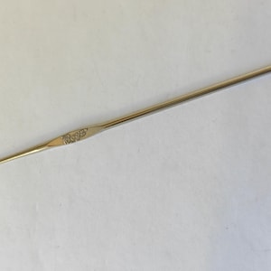 May include: A silver crochet hook with a slender, elongated design. The hook features a pointed end for catching yarn and a slightly curved head. The word "Boye" is engraved on the hook's handle. This tool is used for creating crocheted items.