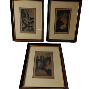 May include: Three framed landscape prints. Each print features a sepia-toned image of a building or natural scene. The frames are dark brown with a gold inner border, and the prints are set against a cream-colored mat.