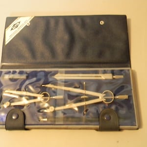 May include: A blue leather case with a clear plastic insert containing a set of drafting compasses. The case has the brand name "ALVIN" printed on it.