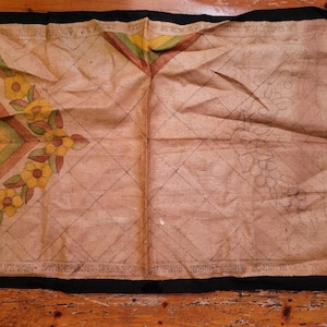 May include: A beige canvas with a black border and a printed design of flowers and geometric shapes. The text "WORK WITH STANDARD BRACE AFTER KNITTING AND  BIG TO WIN" is printed at the bottom.