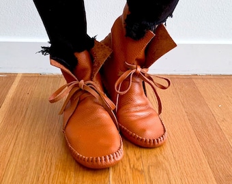 May include: A pair of brown leather ankle boots with laces. The boots have a pointed toe and a low heel.