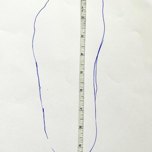 May include: A blue outline of a foot traced on white paper, with a ruler placed alongside. The ruler shows a measurement of approximately 9 inches. The image is for shoe size measurement.