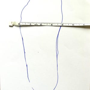 May include: A blue outline of a foot drawn on white paper with a measuring tape placed across the foot. The foot measures approximately 4 inches in length.