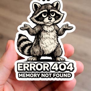 May include: A sticker featuring a cartoon raccoon with a confused expression and outstretched arms. The text "ERROR 404 MEMORY NOT FOUND" is displayed below the raccoon in a white box with a black border.