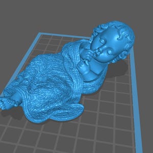 Peut inclure: Une sculpture bleue d'un bébé couché, enveloppé dans une couverture. Le bébé repose sa tête sur sa main, les doigts près de sa bouche. La couverture a un motif texturé. La sculpture est sur une grille.