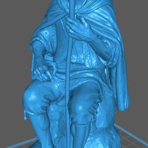 Può includere: Statua blu stampata in 3D di un uomo seduto, che tiene un bastone. La figura indossa un mantello e sandali. La statua è su una base strutturata, con un motivo a griglia visibile in basso.