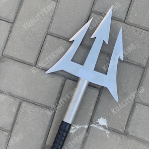May include: A silver trident with three prongs, a silver shaft, and a black textured handle. The trident is a prop or decorative item, possibly for cosplay or themed events.