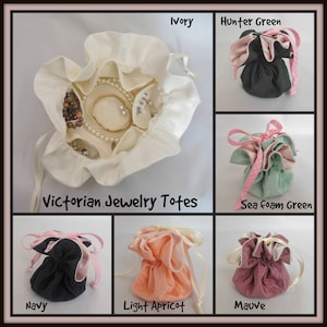 May include: Victorian jewelry totes in ivory, hunter green, sea foam green, navy, light apricot, and mauve. Each tote is a small, ruffled pouch with a drawstring closure and ribbon ties. The ivory tote is open, displaying jewelry.