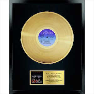 Könnte beinhalten: Eine goldfarbene Schallplatte in einem schwarzen Rahmen. Das mittlere Etikett ist lila und weiß mit dem Text Rush, Moving Pictures und Anthem. Unter der Platte befindet sich eine goldene Plakette mit dem Text Rush - Moving Pictures und Details.