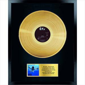 May include: Framed gold record of Nirvana's "Nevermind" album. The record is displayed on a black background within a black frame. A gold plaque below the record provides album details, including the release date and record label.