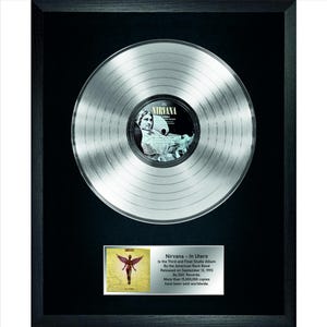 May include: A silver platinum record in a black frame with a black mat. The record features the album cover for Nirvana's "In Utero" album. The album cover features a nude woman with angel wings. The text "Nirvana - In Utero" is printed below the album cover. The text reads: "Is the Third and Final Studio Album by the American Rock Band. Released on September 13, 1993 by DGC Records. More than 15,000,000 copies have been sold worldwide."