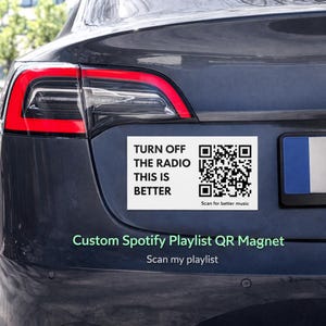 Peut inclure: Un aimant rectangulaire blanc avec le texte "TURN OFF THE RADIO THIS IS BETTER" et un code QR, fixé à l'arrière d'une voiture gris foncé. Il est également écrit "Custom Spotify Playlist QR Magnet".