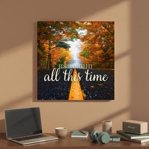 May include: A canvas print showing a road through a forest with colourful autumn leaves. The text "IT'S WORTH IT all this time" is written in white script across the road.