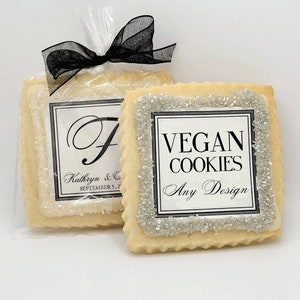 May include: Two square-shaped sugar cookies with white frosting and black lettering. One cookie says "VEGAN COOKIES" and "Any Design". The other cookie has a decorative letter "F" and the text "Kathryn & C SEPTEMBER 5, 2022".