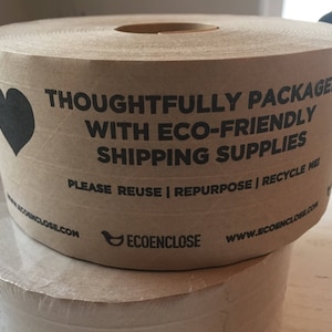 May include: A roll of brown packing paper with a black heart graphic and text that reads "THOUGHTFULLY PACKAGED WITH ECO-FRIENDLY SHIPPING SUPPLIES." The text also includes "PLEASE REUSE | REPURPOSE | RECYCLE ME."