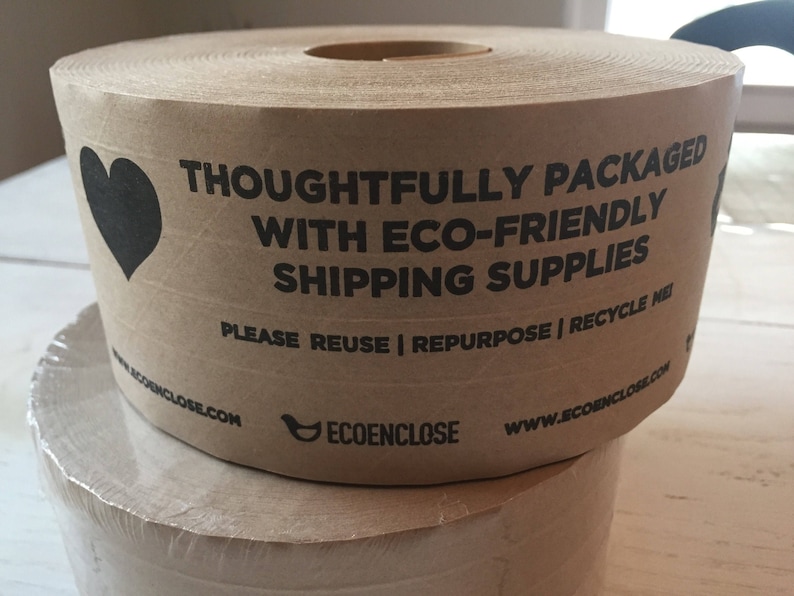 May include: A roll of brown packing paper with a black heart graphic and text that reads "THOUGHTFULLY PACKAGED WITH ECO-FRIENDLY SHIPPING SUPPLIES." The text also includes "PLEASE REUSE | REPURPOSE | RECYCLE ME."