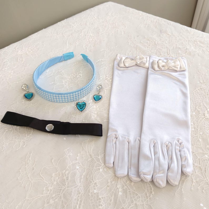May include: A light blue headband with a white checkered pattern, two heart-shaped blue earrings, a black ribbon choker with a central clear stone, and a pair of white satin gloves featuring small white bows at the wrists.