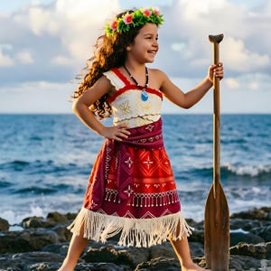 Pode incluir: Um vestido de fantasia com corpete creme com padrões dourados, saia vermelha com desenhos geométricos brancos e bainha com franjas creme. O traje inclui uma coroa de flores, um colar com pingente azul e um remo de madeira.